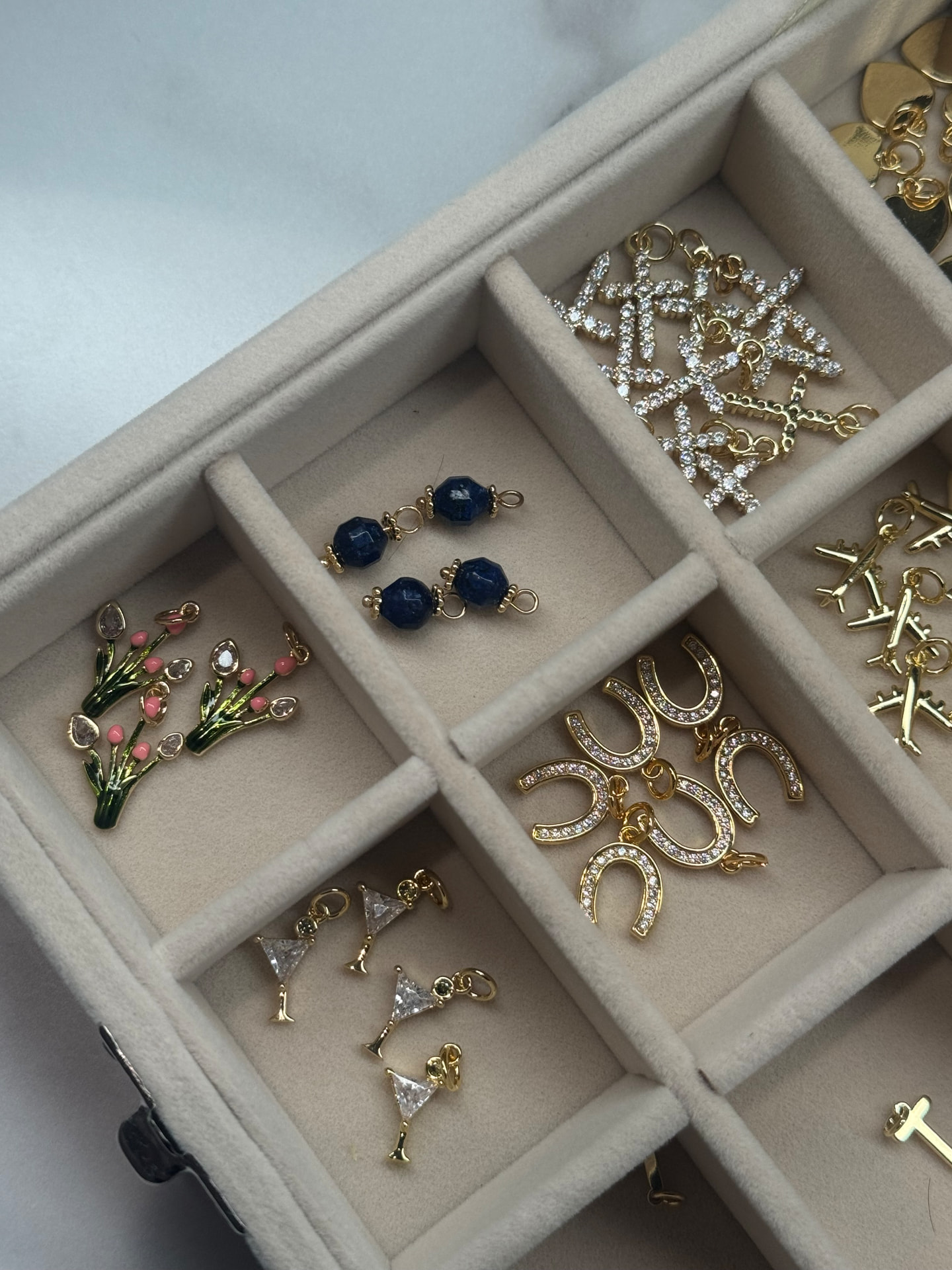 Charm bar with gold charms, horseshoes, flowers, and cocktail glass charms in a velvet tray