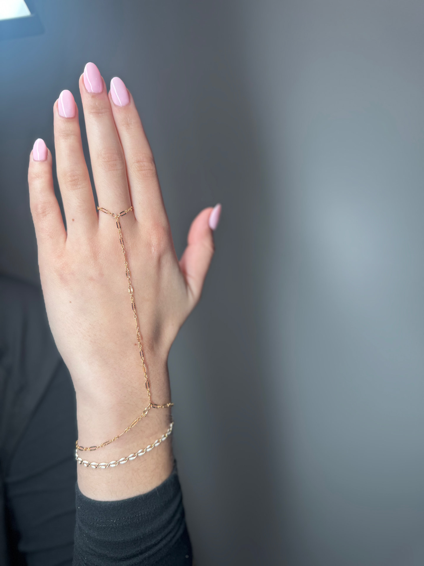 Gold hand chain connecting a ring to a wrist bracelet
