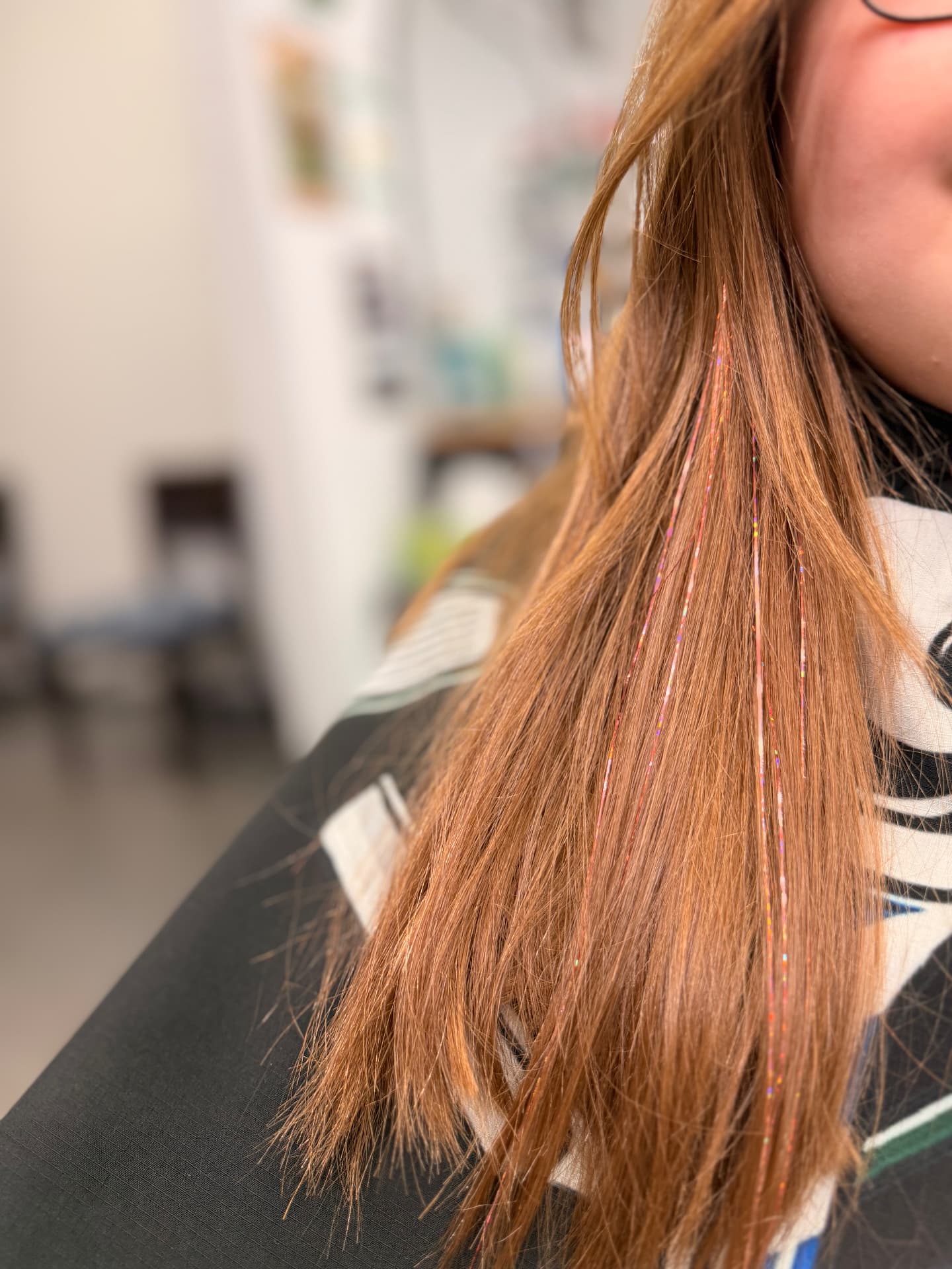 Pink and iridescent hair tinsel strands in auburn hair
