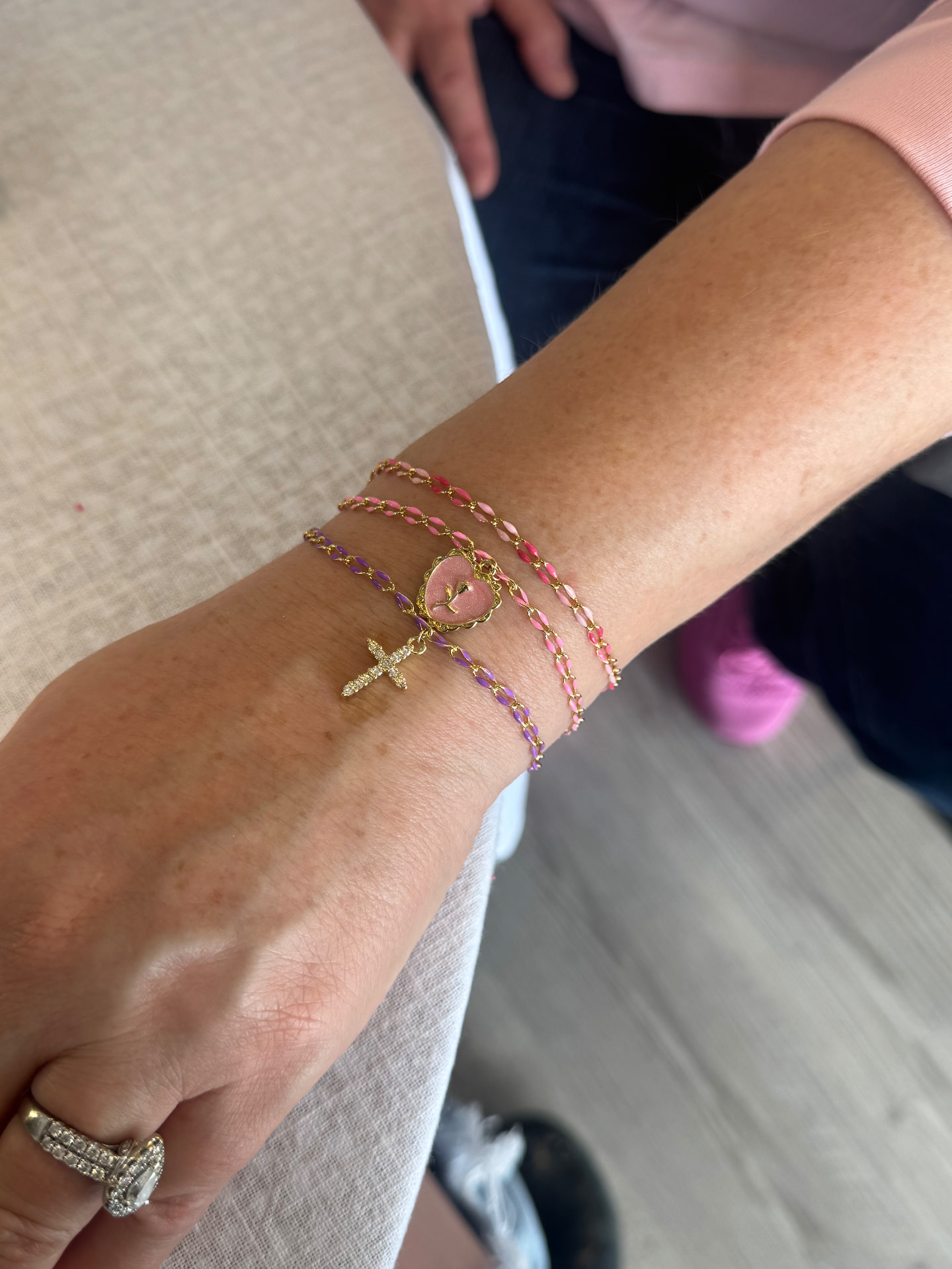 Stacked enamel and gold permanent bracelets on a wrist